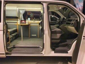 weisser Camper im Showroom, Seitenansicht mit Blick in den Innenraum
